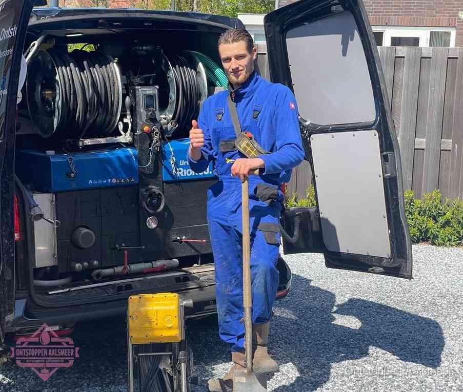 Een monteur bij de werkbus met grote hogedruk-slanghaspels, apparatuur voor hardnekkige afvoerverstoppingen in Aalsmeer