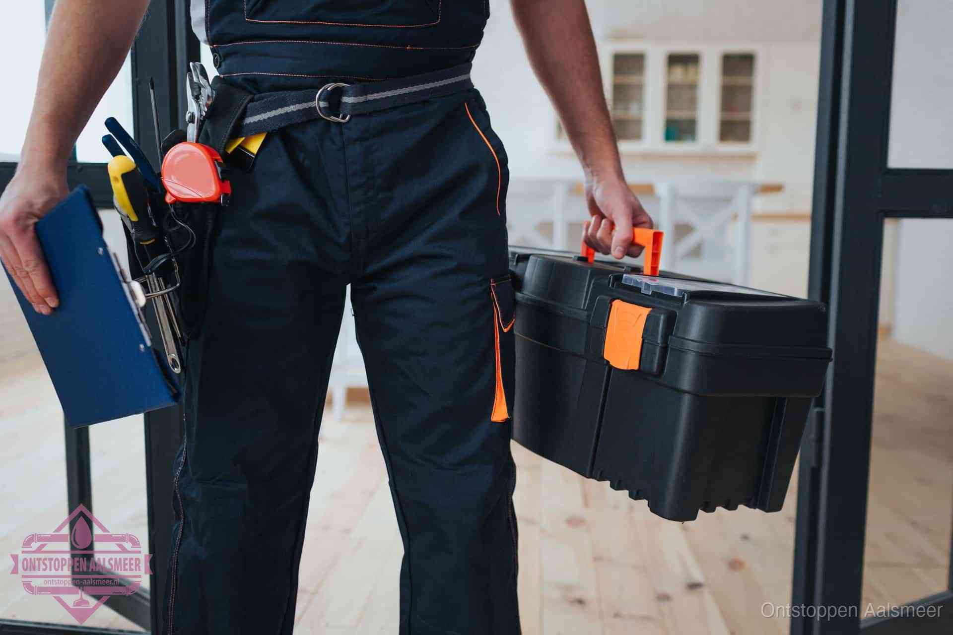 Een monteur met gereedschapsriem en klembord in een keuken, klaar om een transparante prijs voor het gootsteen ontstoppen in Aalsmeer te geven