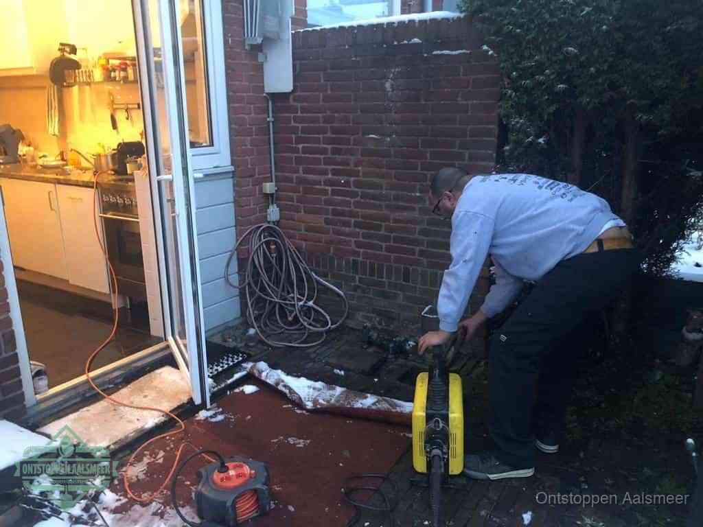 Een monteur werkt buiten bij een open riool-/grondput met een elektrische ontstoppingsmachine om een verborgen afvoerprobleem op te sporen in Aalsmeer