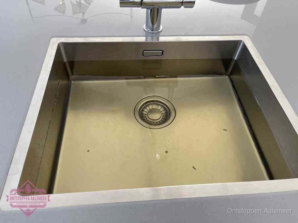 Stilstaand water in een rvs spoelbak dat niet wegloopt, een duidelijk signaal van een gootsteenverstopping in Aalsmeer