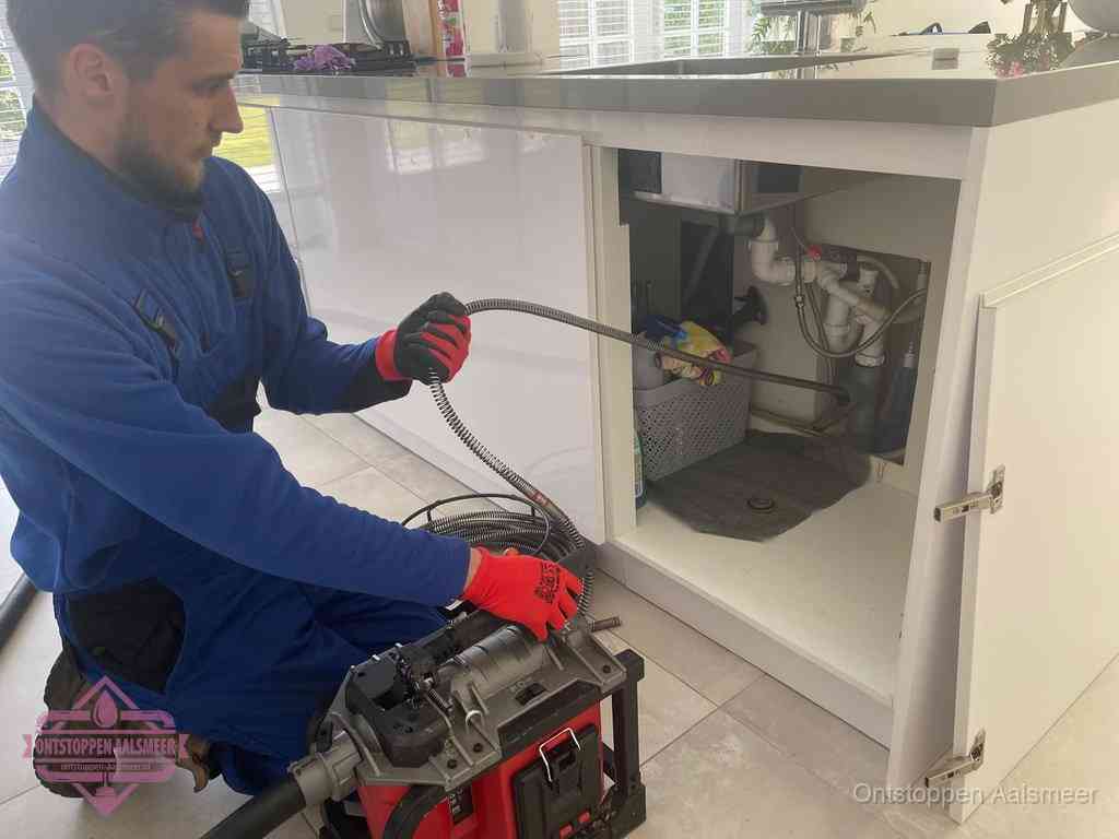Een monteur reinigt de keukenafvoer grondig met een veermachine om terugkerende gootsteenverstoppingen te voorkomen in Aalsmeer