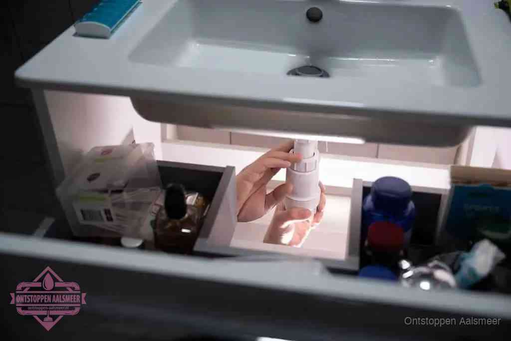Een pompfles met zeep boven een wastafel in de toiletruimte, de warm water en afwasmiddel-methode om de wc te ontstoppen in Aalsmeer