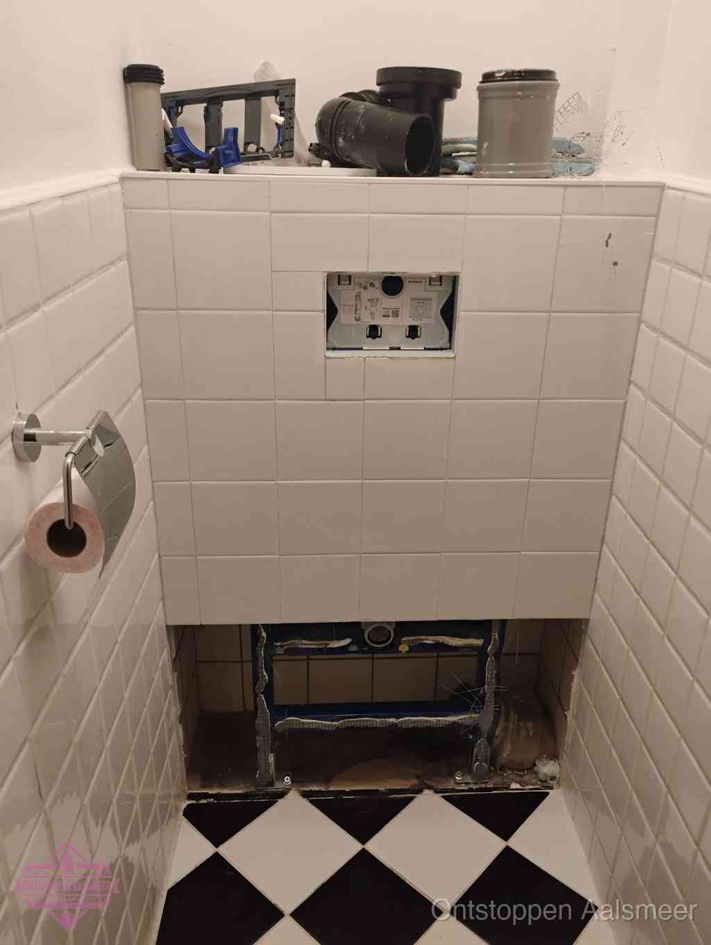 Een toiletruimte waar het hangtoilet en de inbouwreservoir-onderdelen zijn vrijgelegd voor onderhoud, periodiek nazicht voorkomt een wc-verstopping in Aalsmeer
