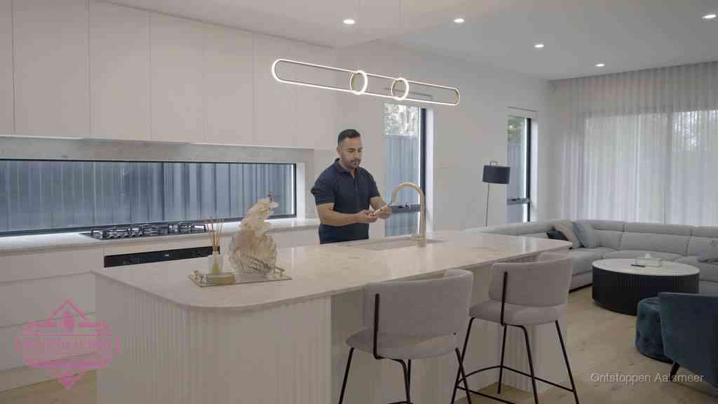 Een bewoner bij de keukenspoelbak die zelf aan de slag gaat met een verstopte gootsteen in Aalsmeer